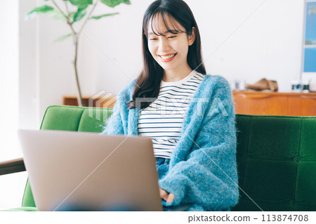 Woman using a computer on the sofa 113874708