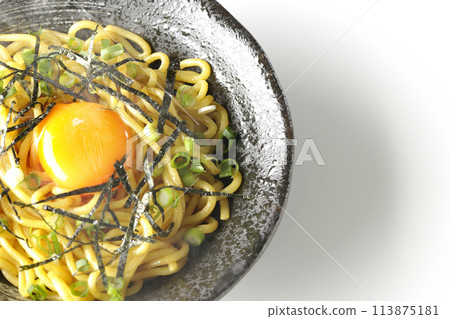 Aerial view of hot oil soba noodles topped with egg yolk, shredded seaweed, and green onions, shot on a white background Aerial view of hot oil soba noodles topped with egg yolk, shredded seaweed, and green onions, shot on a white background 113875181