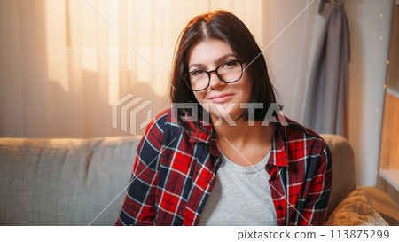 Smart woman. Smiling portrait. Positive attitude. Cheerful casual female student in spectacles sitting sunny light room interior. 113875299