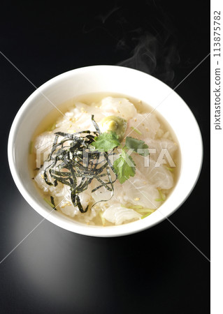 頭頂上拍攝的是滾燙的海鯛茶泡飯,配上大石湯,上面放著三葉葉、海藻絲和芥末,背景是黑色 頭頂上拍攝的是滾燙的海鯛茶泡飯,配上大石湯,上面放著三葉葉、海藻絲和芥末,背景是黑色 113875782