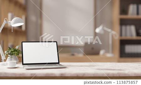 The table showcases a white-screen laptop computer in a contemporary office. The table showcases a white-screen laptop computer in a contemporary office. 113875857