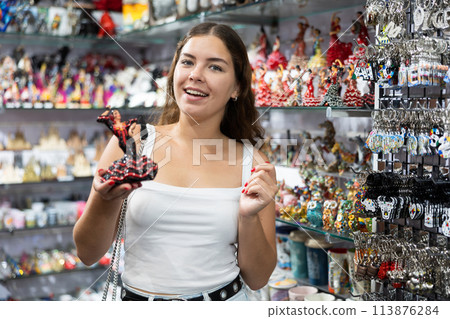 Female buyer holds in hands tests figurine she-dancer flamenco in memorable gifts shop Female buyer holds in hands tests figurine she-dancer flamenco in memorable gifts shop 113876284