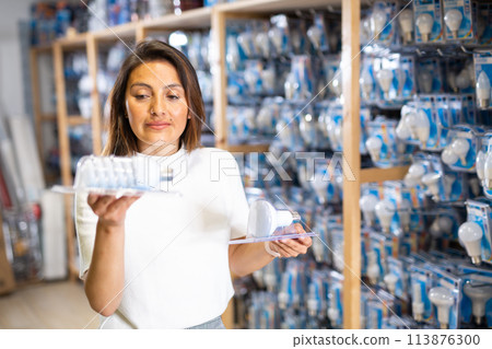 Young woman choosing light bulb at shop 113876300