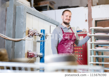 Artisan presenting ceramics ready for drying or firing in pottery workshop 113876390