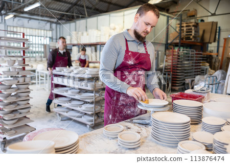 Potter cleaning plates with sponge before finishing 113876474