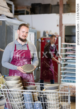 Young man posing with ceramic dishes Young man posing with ceramic dishes 113876504