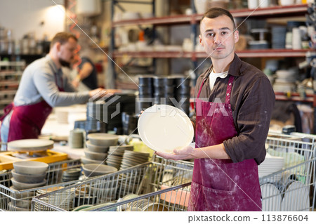 Young man posing with ceramic dishes Young man posing with ceramic dishes 113876604