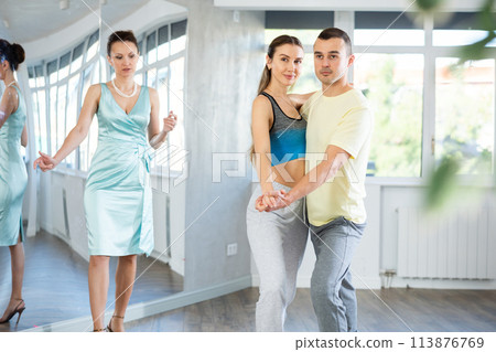 Woman and man in sportswear performing tango at dance rehearsal 113876769