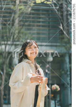 A woman refreshing herself while walking through a fashionable town A woman refreshing herself while walking through a fashionable town 113876791