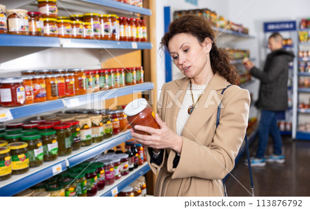 Adult woman chooses lecho in store 113876792