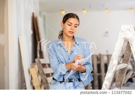 Female architect matching check list during repair works Female architect matching check list during repair works 113877082