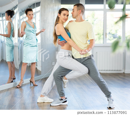 Couple rehearsing elegant tango under guidance of female teacher 113877091