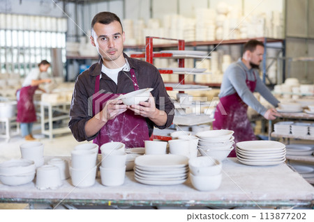Artisan meticulously examining slipcast ceramic plates in workshop Artisan meticulously examining slipcast ceramic plates in workshop 113877202
