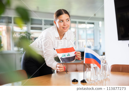 Young lady sets miniatures flags of Russia and Iraq before international negotiations Young lady sets miniatures flags of Russia and Iraq before international negotiations 113877273
