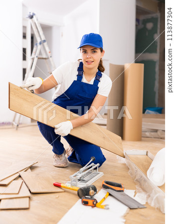 Female builder checking laminate planks before installation 113877304
