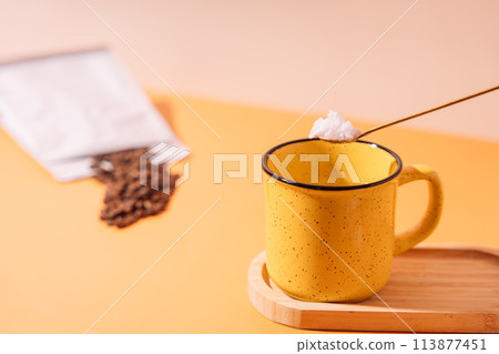 Bulletproof coffee with coconut oil. Yellow mug with a spoon of sugar and coffee beans 113877451