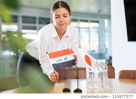 Businesswoman placing flags of Iraq and Japan on table before negotiations Businesswoman placing flags of Iraq and Japan on table before negotiations 113877577
