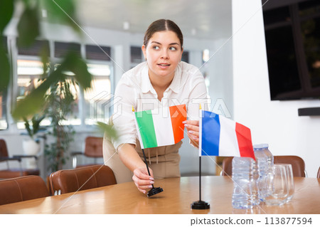 Young woman puts flags of Italy and France on table Young woman puts flags of Italy and France on table 113877594