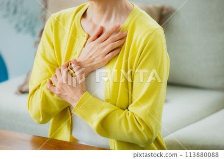 Middle-aged woman in living room feeling unwell 113880088