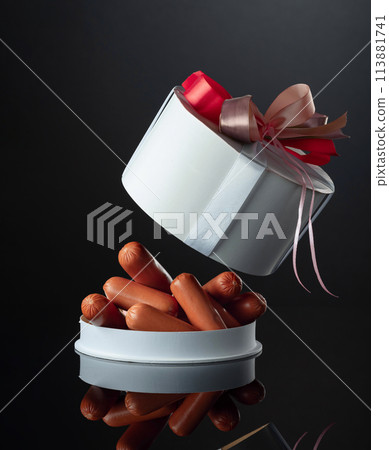 Opened gift box with sausages on a black background. Opened gift box with sausages on a black background. 113881741