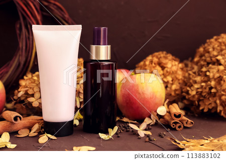 moisturizing cream pink tube bottle with black screw cap, brown cosmetic spray bottle, apples, cinnamon, dried flower. Body skincare, shampoo, hair conditioner packaging mockup in autumn composition 113883102