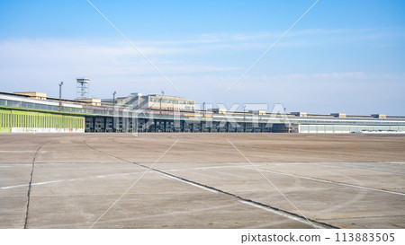 Clear blue skies over the historic Berlin Tempelhof Airport in Germany, showcasing the vast airport tarmac and iconic terminal building with hangars. Clear blue skies over the historic Berlin Tempelhof Airport in Germany, showcasing the vast airport tarmac and iconic terminal building with hangars. 113883505