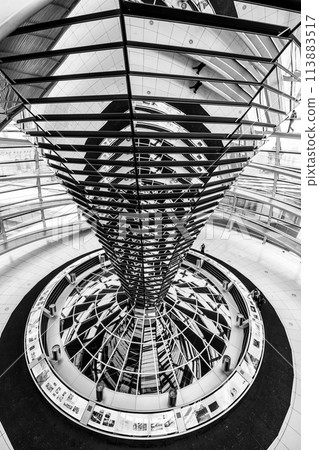 Inside view of the Reichstag glass dome in Berlin showing the mirrored central column and steel framework. Black and white image. 113883517