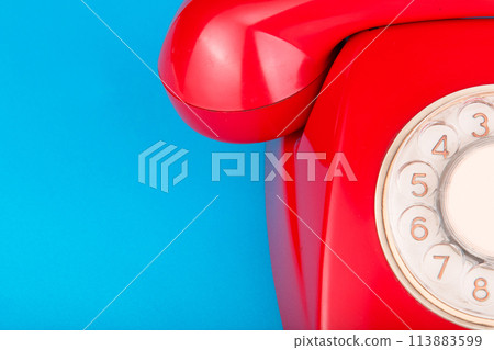 Old red telephone on a blue background Old red telephone on a blue background 113883599