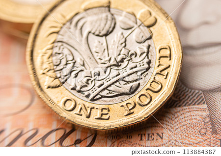 one pound coin and a 10 pound bill 113884387