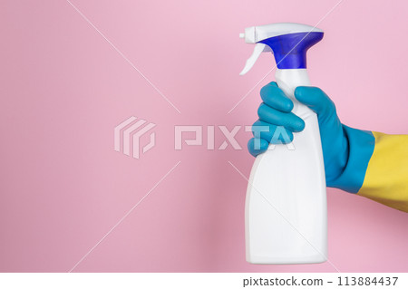 A hand with cleaning gloves holding a spray can on a yellow background 113884437