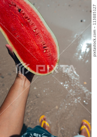 red watermelon in hand at sea red watermelon in hand at sea 113885127
