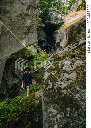 man tourist hiking by rocks on forest 113885512