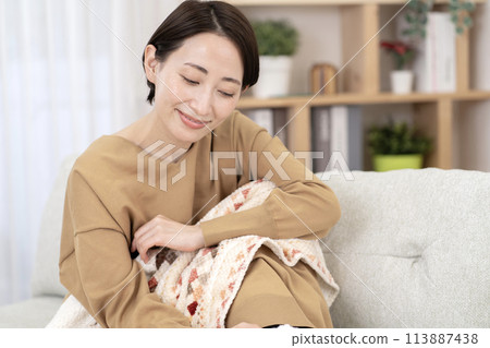一個女人在客廳放鬆，溫暖而對寒冷敏感 113887438