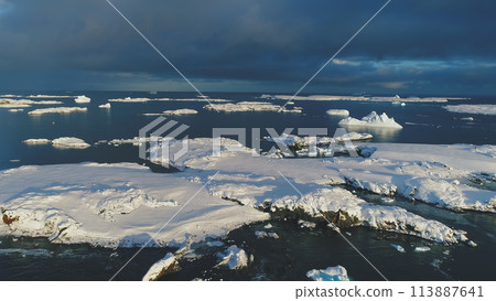 Antarctica aerial front view over snowy islands. Icebergs in ocean water in Antarctic polar summer. Beautiful polar landscape. Drone forward flight. 113887641