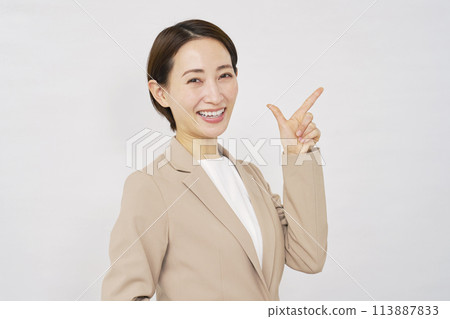 Middle-aged business woman pointing down on white background Middle-aged business woman pointing down on white background 113887833