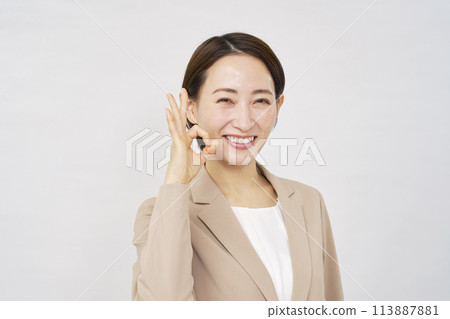 Middle-aged business woman giving an OK sign white background Middle-aged business woman giving an OK sign white background 113887881