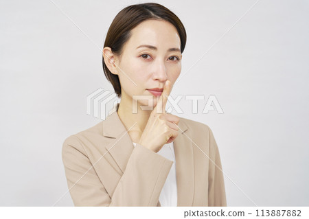 Middle-aged businesswoman making a secret gesture on white background Middle-aged businesswoman making a secret gesture on white background 113887882