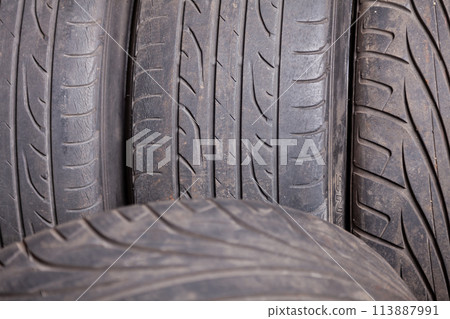 Automobile composition made up stack of tires and wheel with shiny disc in a car service before seasonal replacement or after breaking through. Automobile composition made up stack of tires and wheel with shiny disc in a car service before seasonal replacement or after breaking through. 113887991