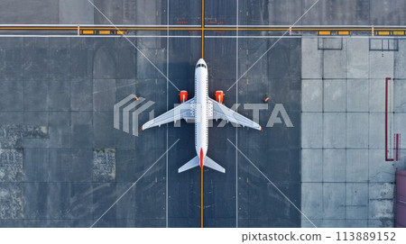 Top down view on commercial airplane docking in terminal in the parking lot of the airport apron, waiting for services maintenance, refilling fuel services after airspace lock down 113889152