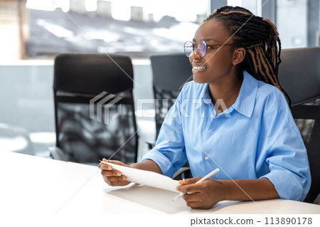 Smiling woman sitting at desk in office with paper documents 113890178
