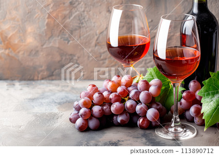 Wine bottle, glass and grapes isolated on a granite background. Rose wine splashing in glassware 113890712