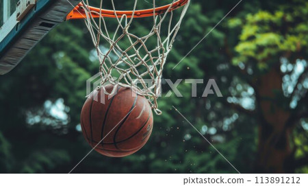 Basketball ball entered in the basket touching the net. Playing in the street on outdoor court, close up 113891212