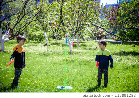 Two friends are playing tetherball swing ball game in summer camping. Two boy brother happy leisure healthy active time outdoors concept 113891288