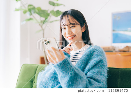 Woman using smartphone on sofa Woman using smartphone on sofa 113891470