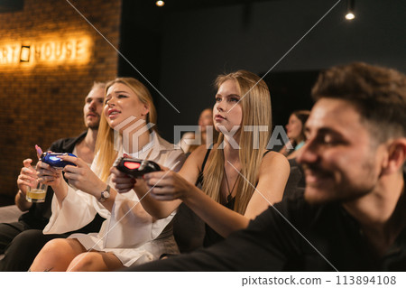 Man spectator enthralled by women performance in video game Man spectator enthralled by women performance in video game 113894108