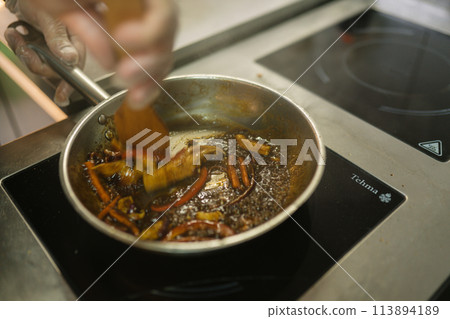 Cook stirs sizzling medley of frying vegetables with spatula 113894189