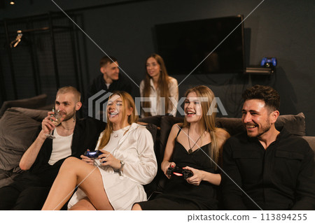 Women share laughter immersing in realm of video games 113894255