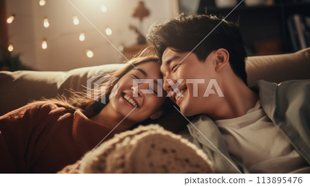 A young couple shares a cozy moment on the couch, radiating warmth and joy. 113895476