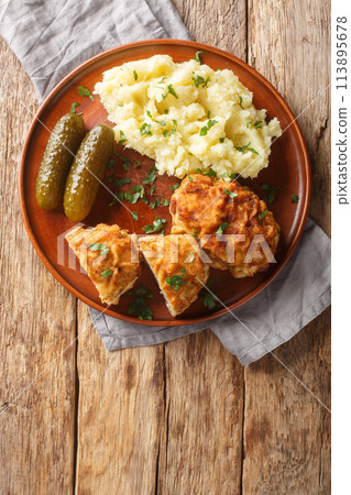 Dutch Schnitzel or Holandsky rizek in Czech, is a combination of delicious pork meat with shredded cheese, herbs served with mashed potatoes closeup on the plate. Vertical top view Dutch Schnitzel or Holandsky rizek in Czech, is a combination of delicious pork meat with shredded cheese, herbs served with mashed potatoes closeup on the plate. Vertical top view 113895678