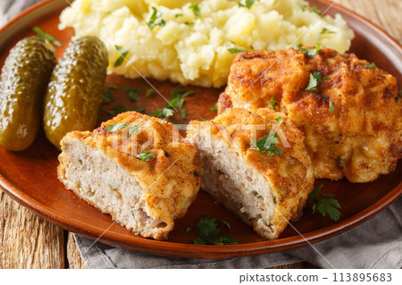 Holandsky rizek Czech pork meatball with cheese, breaded, served with mashed potatoes and pickled close-up in a plate. Horizontal Holandsky rizek Czech pork meatball with cheese, breaded, served with mashed potatoes and pickled close-up in a plate. Horizontal 113895683
